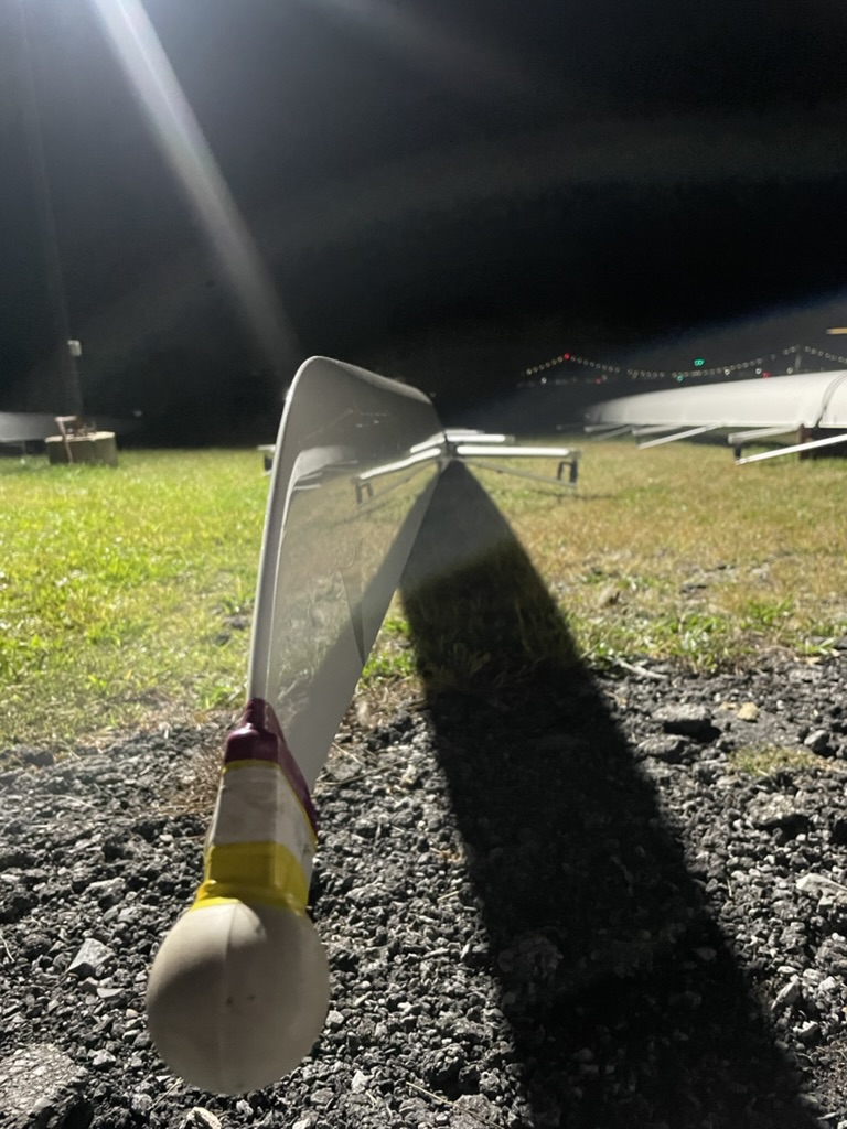 An oar on the ground under the boathouse lights at night
